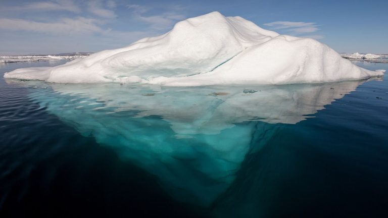 broken arctic sea ice floating on dark ocean water